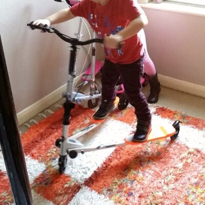 January 2016, photo of Ayrton & Gabrielle Abreu on their tri-scooters, inside their bedroom at their home with daddy. This photo is part of a group that will help provide some perspective to layout & dimensions for their living room. This photo faces the front wall of the bedroom. Click on it to expand.